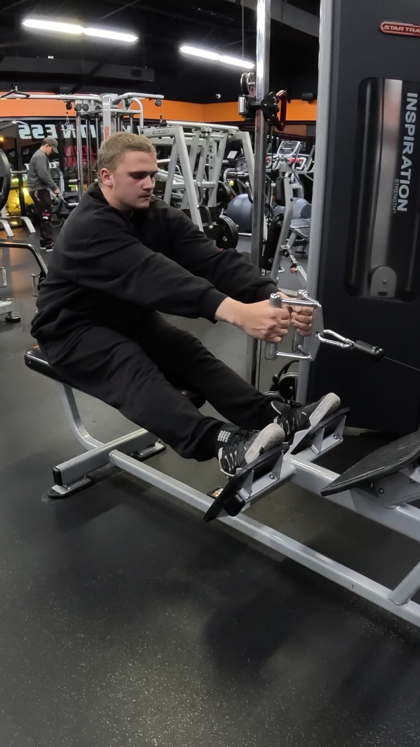 Markus holding a cable row handle at a seated row station.